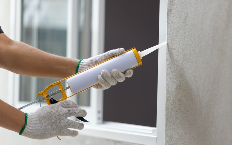 A person caulking a window frame, WyattWorks Cleveland.