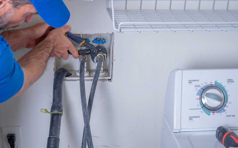 A WyattWorks service professional working on washing machine plumbing in Cleveland, OH.