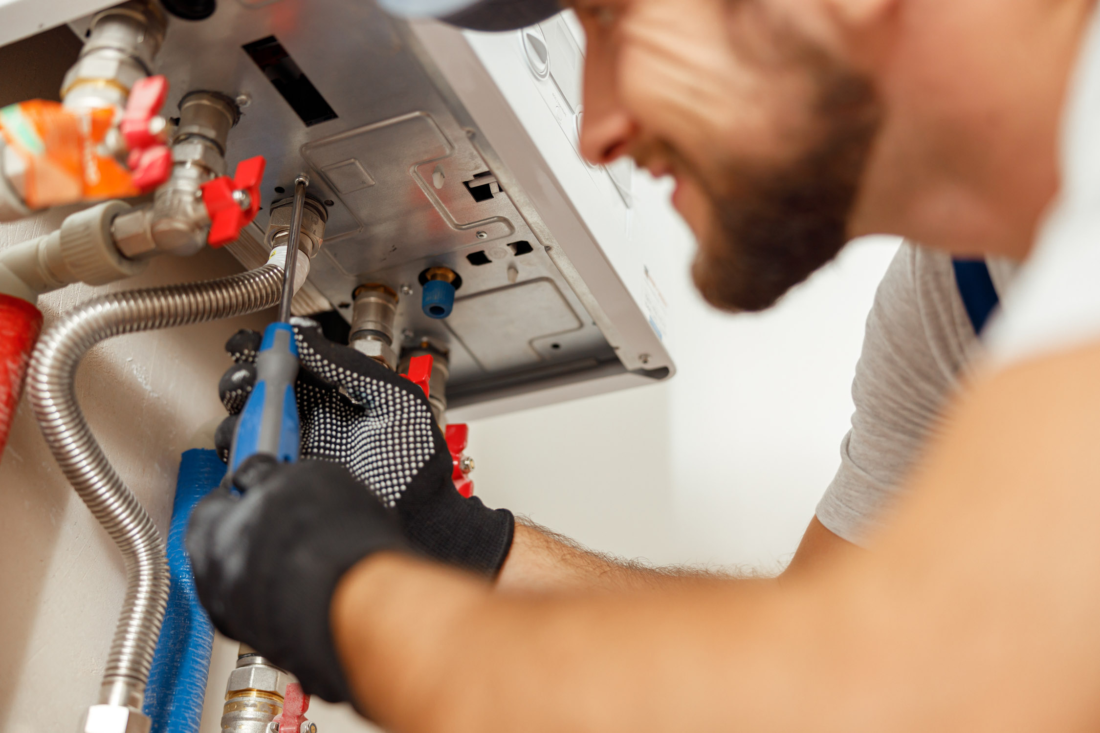 A service provider in a blue shirt from WyattWorks working on a water heater in a residential home.